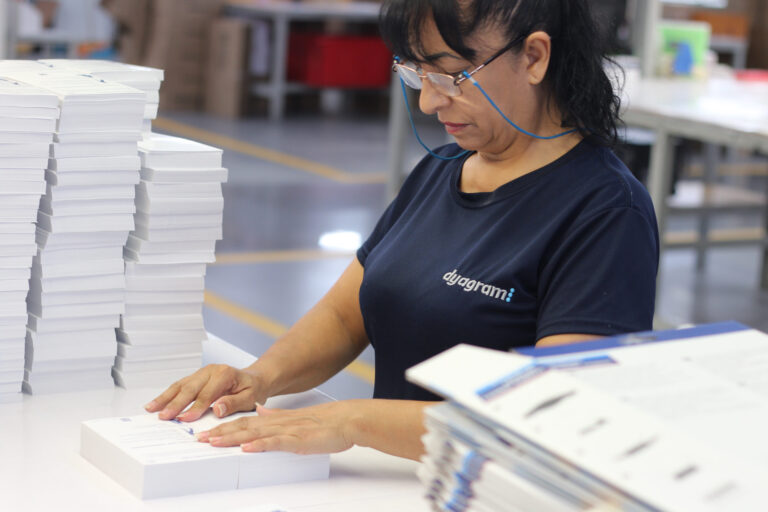 Operadora en área de acabado revisando pliegos impresos en Dyagram